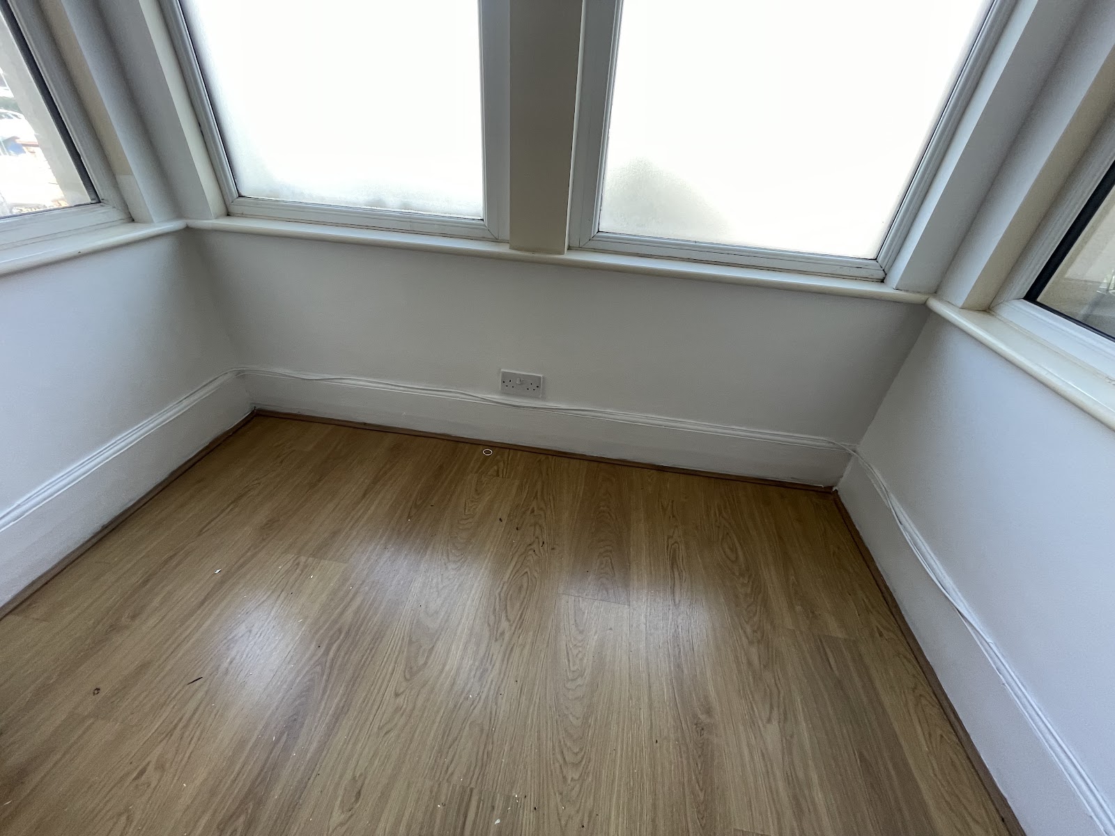 The same bay window after treatment: clean white walls and new oak flooring