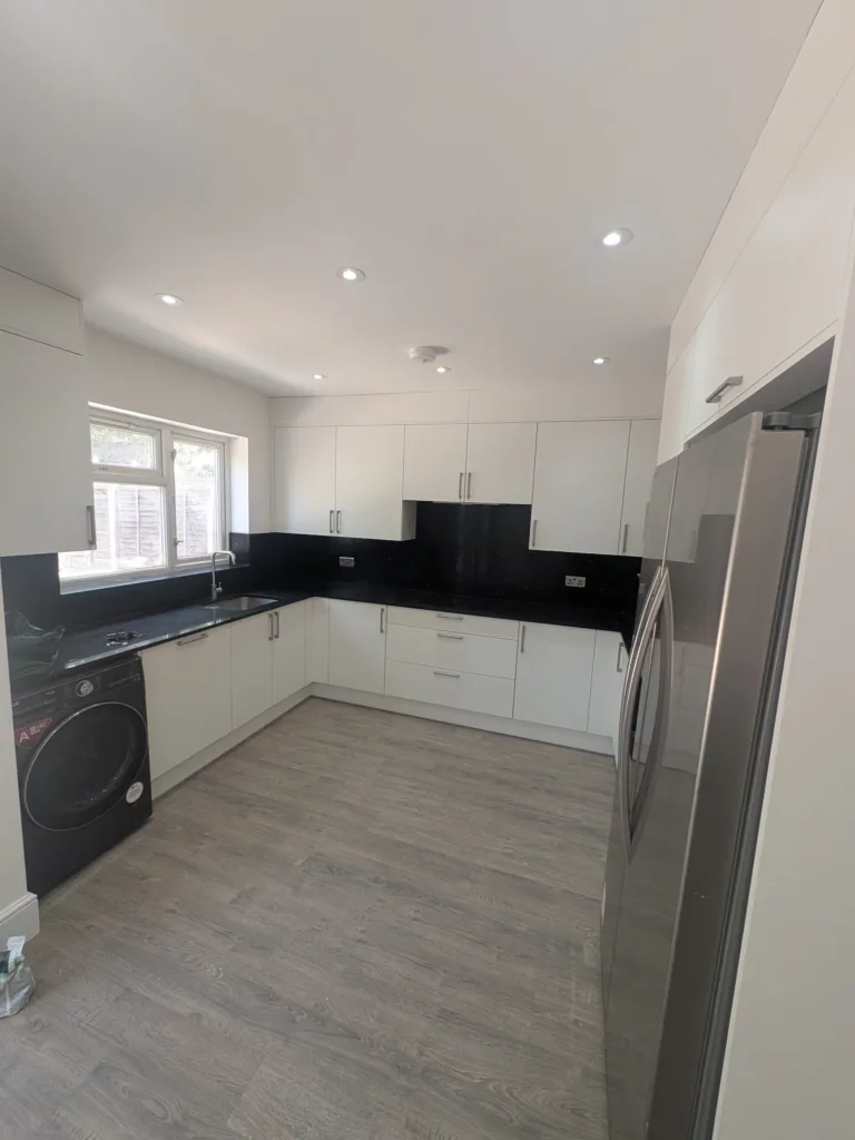 The same Edgware HA8 kitchen finished, with black granite worktop and full-height splashback
