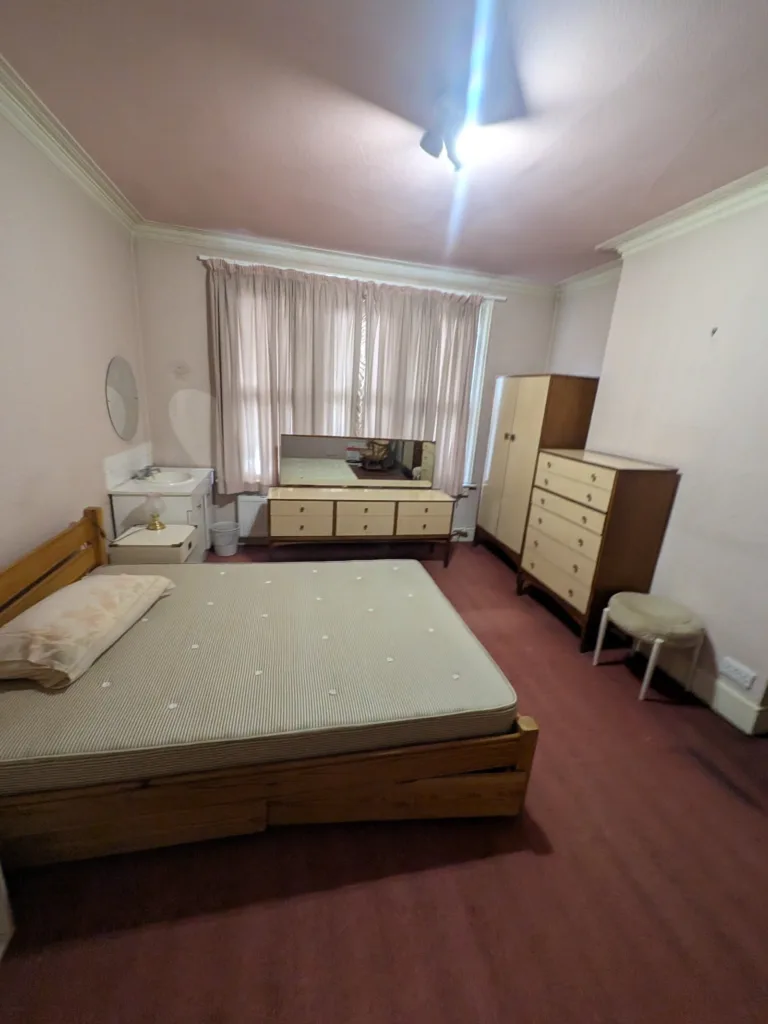 Bedroom in Golders Green NW11 before redecoration, with pink ceiling and worn maroon carpet