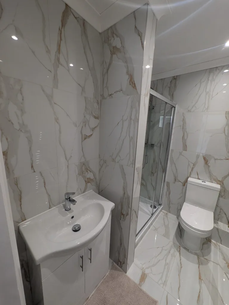 The refitted Pinner HA5 bathroom, tiled in white and gold marble-effect porcelain