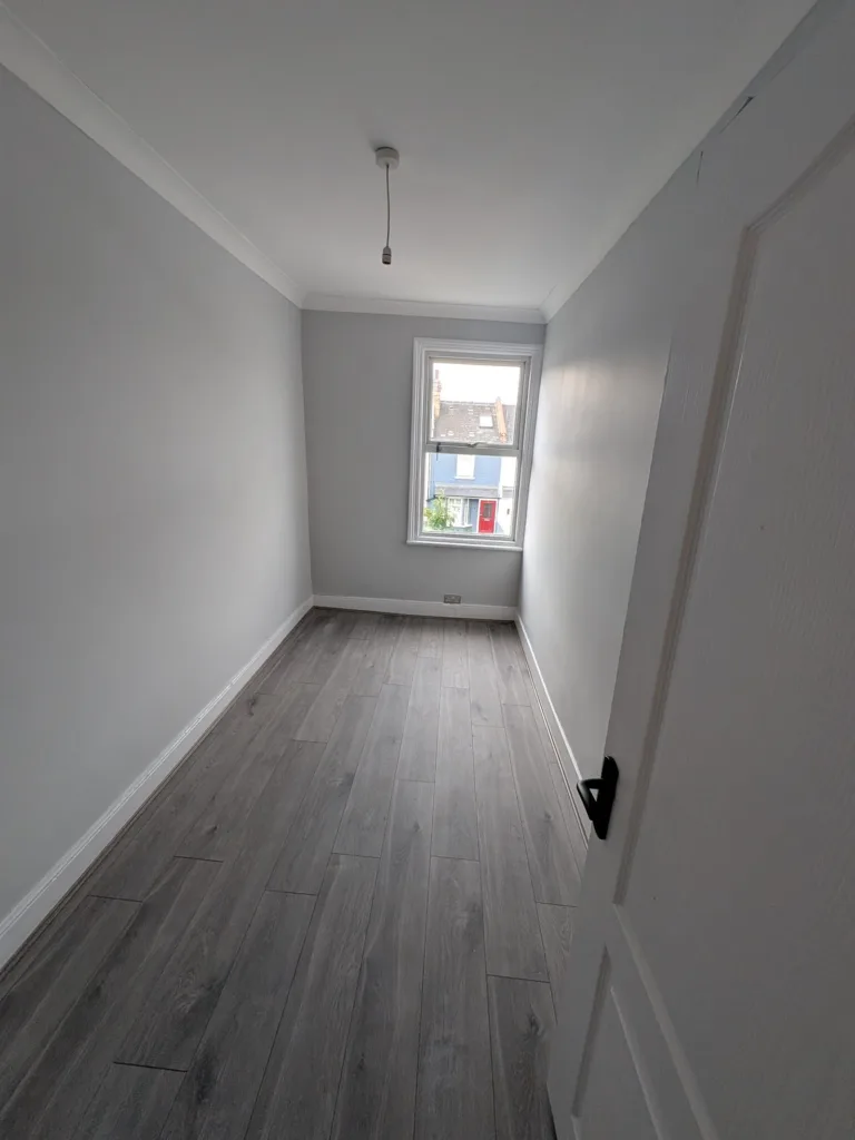 The same Willesden NW10 bedroom repainted, with new grey flooring and a new pendant light